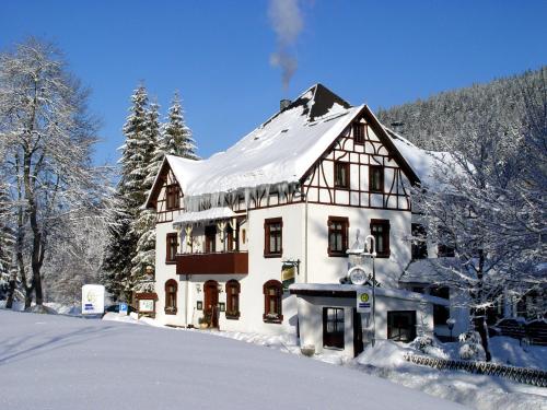 une grande maison recouverte de neige dans l'établissement Gasthof und Pension Hammerschänke, à Wildenthal