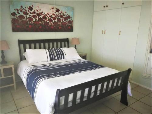 uma cama grande num quarto com um quadro na parede em Scottburgh beach house em Scottburgh