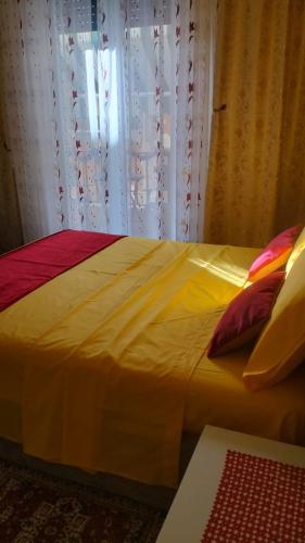 a yellow bed with two pillows and a window at La Casa di Sonia in Savona
