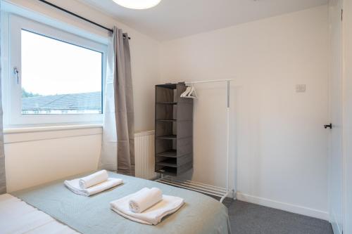 ein Schlafzimmer mit einem Bett mit zwei Handtüchern darauf in der Unterkunft Modern 4 Bed House-Free Parking in Uphall