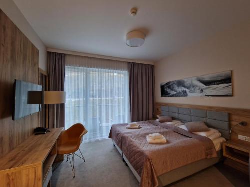 a bedroom with a bed and a desk and a window at Aparthotel Czarna Góra 239 in Sienna