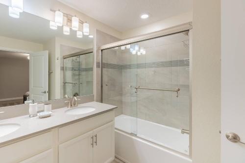 a bathroom with two sinks and a glass shower at Family 4BR w Private Pool near Disney Parks in Kissimmee