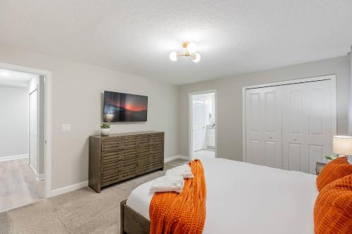 a bedroom with a large bed and a tv at Family 4BR w Private Pool near Disney Parks in Kissimmee