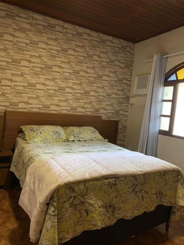een slaapkamer met een bed en een bakstenen muur bij Flavia Aluguel Temporada in Cabo Frio