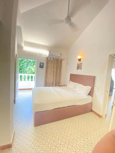 a bedroom with a bed and a large window at sea shore guest house morjim beach in Morjim