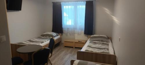 a room with two beds and a table and a window at Jarzębinowy Agroturystyka in Braniewo