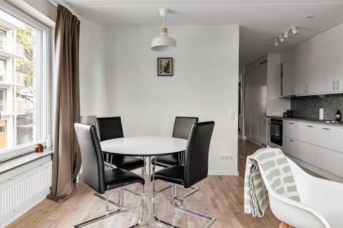 uma cozinha com uma mesa branca e cadeiras pretas em Stylish Urban Home in Stockholm em Estocolmo