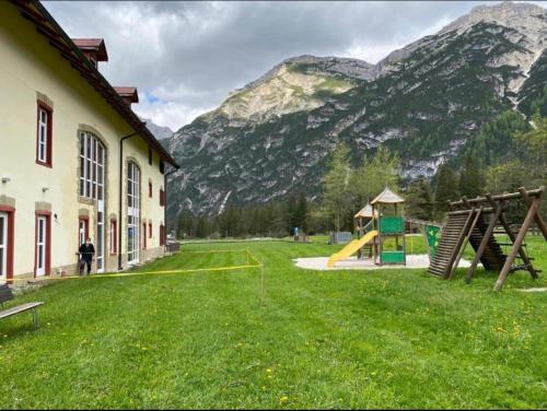 a building with a playground in front of a mountain at Ploner villaggio Turistico in Dobbiaco