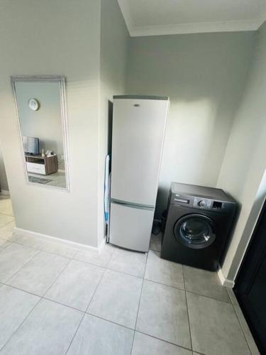 a kitchen with a refrigerator and a washing machine at Ice Holiday Home in Kiddʼs Beach
