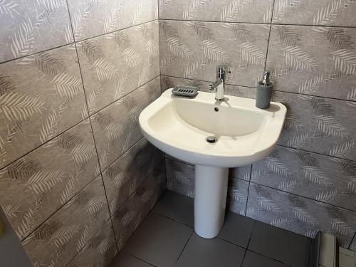 a bathroom with a white sink in a tiled wall at Cottage Karanikola in Sikia