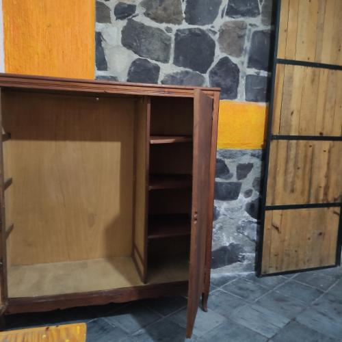 a wooden cabinet with a shelf in front of a stone wall at Casa ampliación piloto in Mexico City