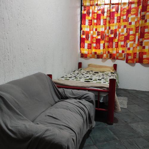 a bed and a couch in a room with a curtain at Casa ampliación piloto in Mexico City