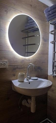 a bathroom with a sink and a round mirror at Захарова Оселя БАСЕЙН на території є Чан - Джакузі in Slavske