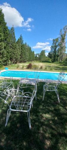 a table and chairs in front of a swimming pool at La Cabañita in Colonia Caroya