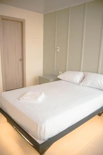 1 cama grande con sábanas blancas y almohadas. en Hotel Amazonas Suite , habitación sencilla en Nueva Loja