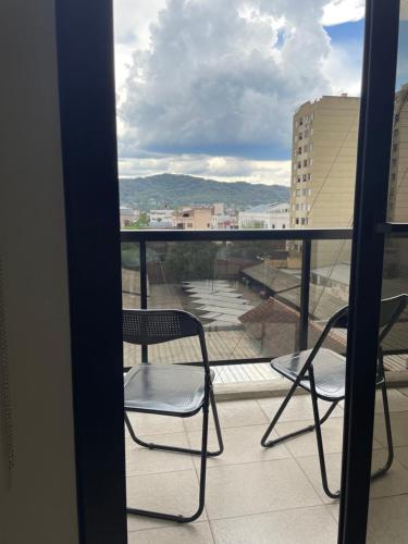 ein Balkon mit zwei Stühlen und Blick auf die Stadt in der Unterkunft Departamento céntrico Belgrano II in San Salvador de Jujuy