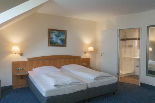 Schlafzimmer mit einem Bett mit weißer Bettwäsche in der Unterkunft Hotel Daniel in München