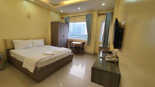 a bedroom with a bed and a television and a table at Khách Sạn Thadico 9 in Ho Chi Minh City