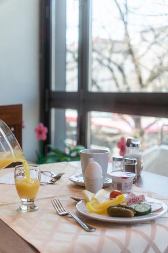 a table with a plate of food and a glass of orange juice at Hotel Daniel in Munich