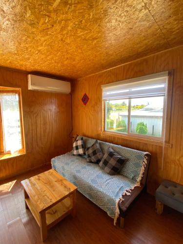 Habitación pequeña con cama y ventana en Cabañas Los Queltehues, en Chacao Viejo