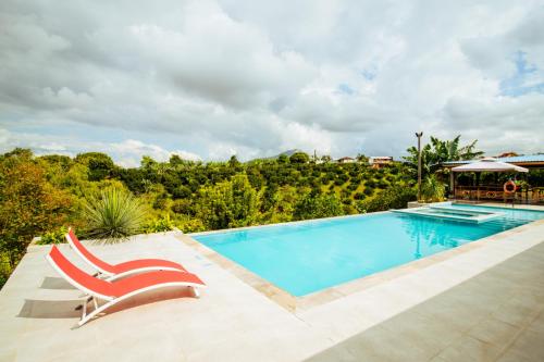 a swimming pool with a red chair next to a pool at Finca Nuevo Monarca in Pereira
