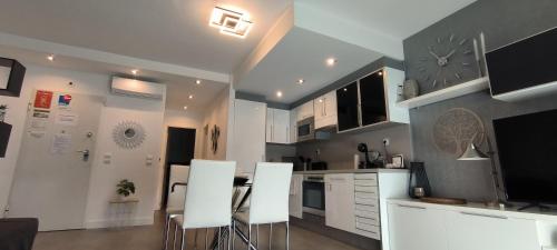 a kitchen with white cabinets and white stools at Denia Beach Apartament Jardín privado y piscina in El Verger