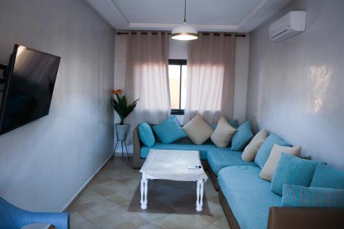 a living room with a blue couch and a table at Baya view surfside in Aourir