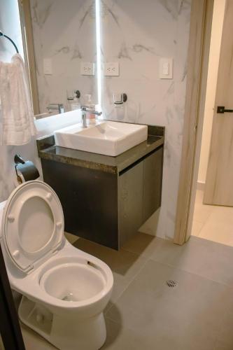 a bathroom with a white toilet and a sink at Hotel Amazonas Suite, Habitación con literas in Nueva Loja