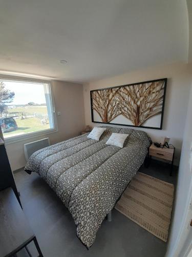 - une chambre dotée d'un lit avec une photo d'arbre sur le mur dans l'établissement La palmeraie de brévy, à Réville