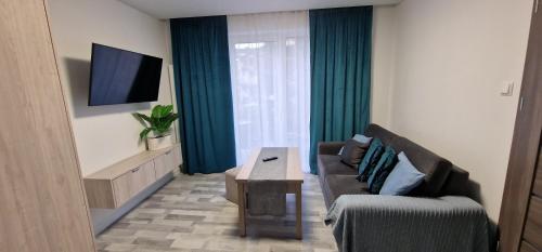 ein Wohnzimmer mit einer Couch, einem Tisch und einem Fernseher in der Unterkunft Angel in Kołobrzeg