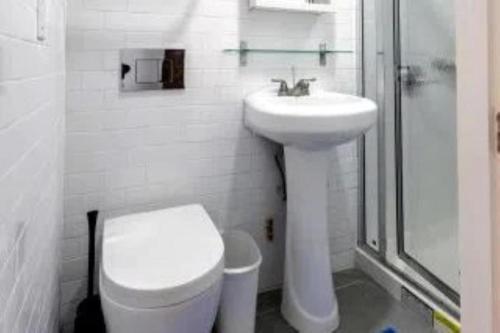 a white bathroom with a toilet and a sink at Beautiful 3 BR Apartment in New York