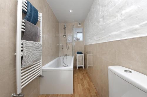 a bathroom with a white tub and a shower at Dairy Cottage Dog friendly cottage with private courtyard and wood burner in Dumfries and Galloway - Contractors welcome in Glenluce