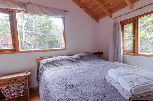um quarto com uma cama e duas janelas em Cabaña Dakota, Ushuaia em Ushuaia
