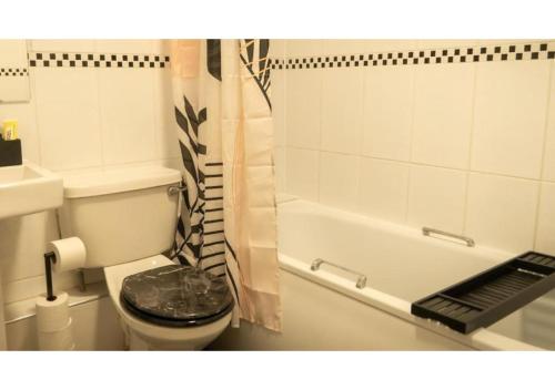 W łazience znajduje się toaleta oraz wanna z zasłoną prysznicową. w obiekcie Clifton’s Cosy Escape w Bristolu