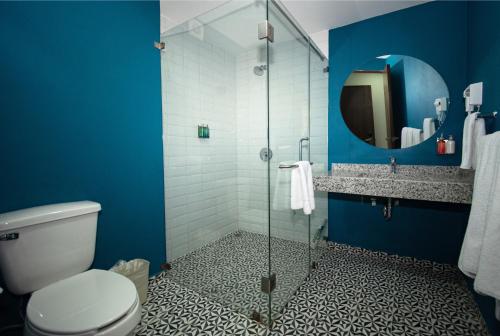 baño azul con aseo y ducha de cristal en Vista Express Guadalajara Expo, en Guadalajara