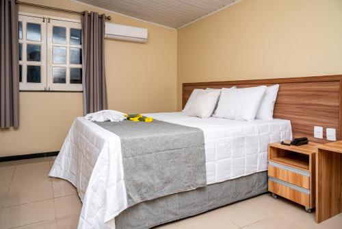 a bedroom with a bed with white sheets and a window at Pousada Vida de Rio in Neópolis