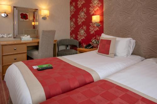 a hotel room with two beds and a desk at Best Western York House Hotel in Eastbourne
