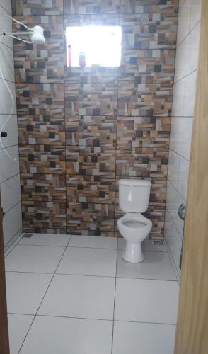 a bathroom with a toilet and a brick wall at Casa da Cris em Praia do Grauçá com Wi-Fi, ar condicionado e garagem in Caravelas