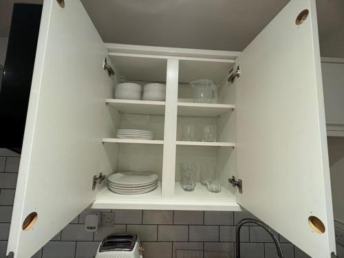 a kitchen cabinet with plates and dishes in it at Rentals Leicester 2 - Free Street Parking in Leicester