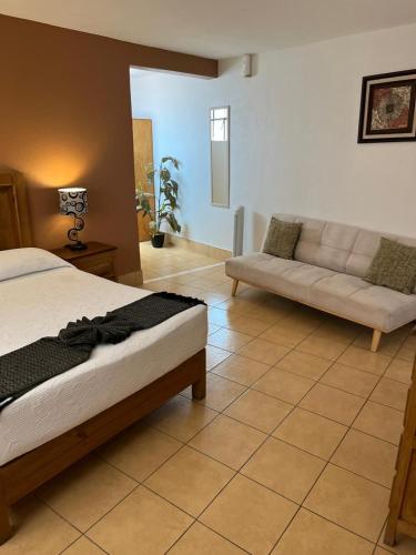 a bedroom with a bed and a couch at Hotel Jardín del Cantador in Guanajuato