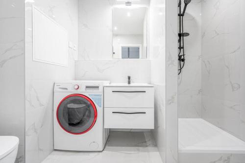een witte badkamer met een wasmachine en een wastafel bij J Komfortný byt na skok od centra in Košice
