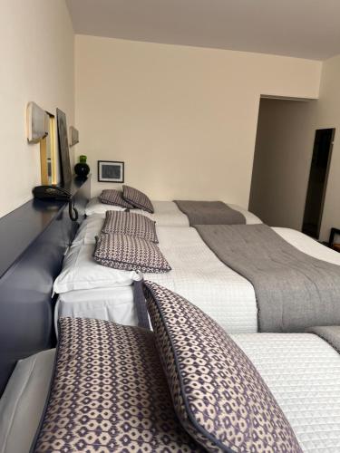 a row of beds in a room with pillows at Le Téméraire Hôtel in Charolles