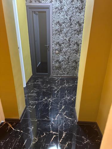 a hallway with a black marble floor and a door at Apartment in Yerevan