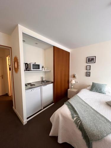 a bedroom with a bed and a small kitchen at Le Téméraire Hôtel in Charolles