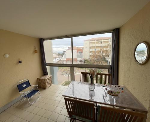 une salle à manger avec une table et une grande fenêtre dans l'établissement Plages & Marina - joli T2 à 200m des plages Sète, à Sète