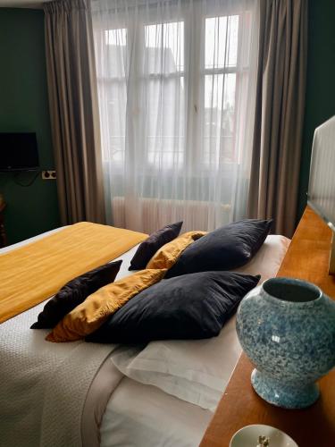 a bedroom with a bed with pillows and a window at Le Téméraire Hôtel in Charolles