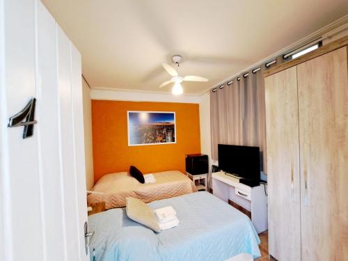 a bedroom with two beds and a flat screen tv at SP Guest House in São Paulo