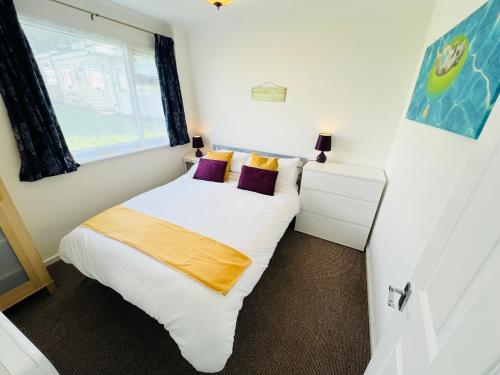 a small bedroom with a white bed and a window at 2 Bedroom Chalet SB113, Sandown Bay, Isle of Wight in Brading