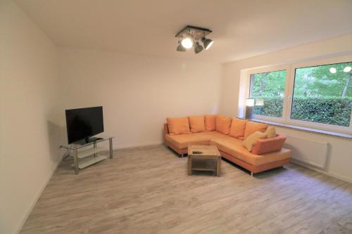 a living room with an orange couch and a flat screen tv at Riverside: Messe/Business/FeWo in Leichlingen