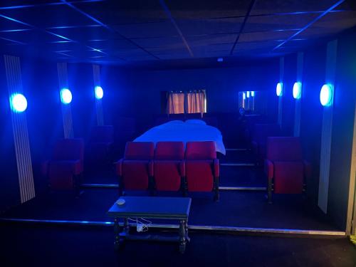 niebieski pokój z czerwonymi krzesłami i łóżkiem w obiekcie Cinema Paradiso - Appartement de charme avec Sauna, Hammam, spa w mieście Issoudun